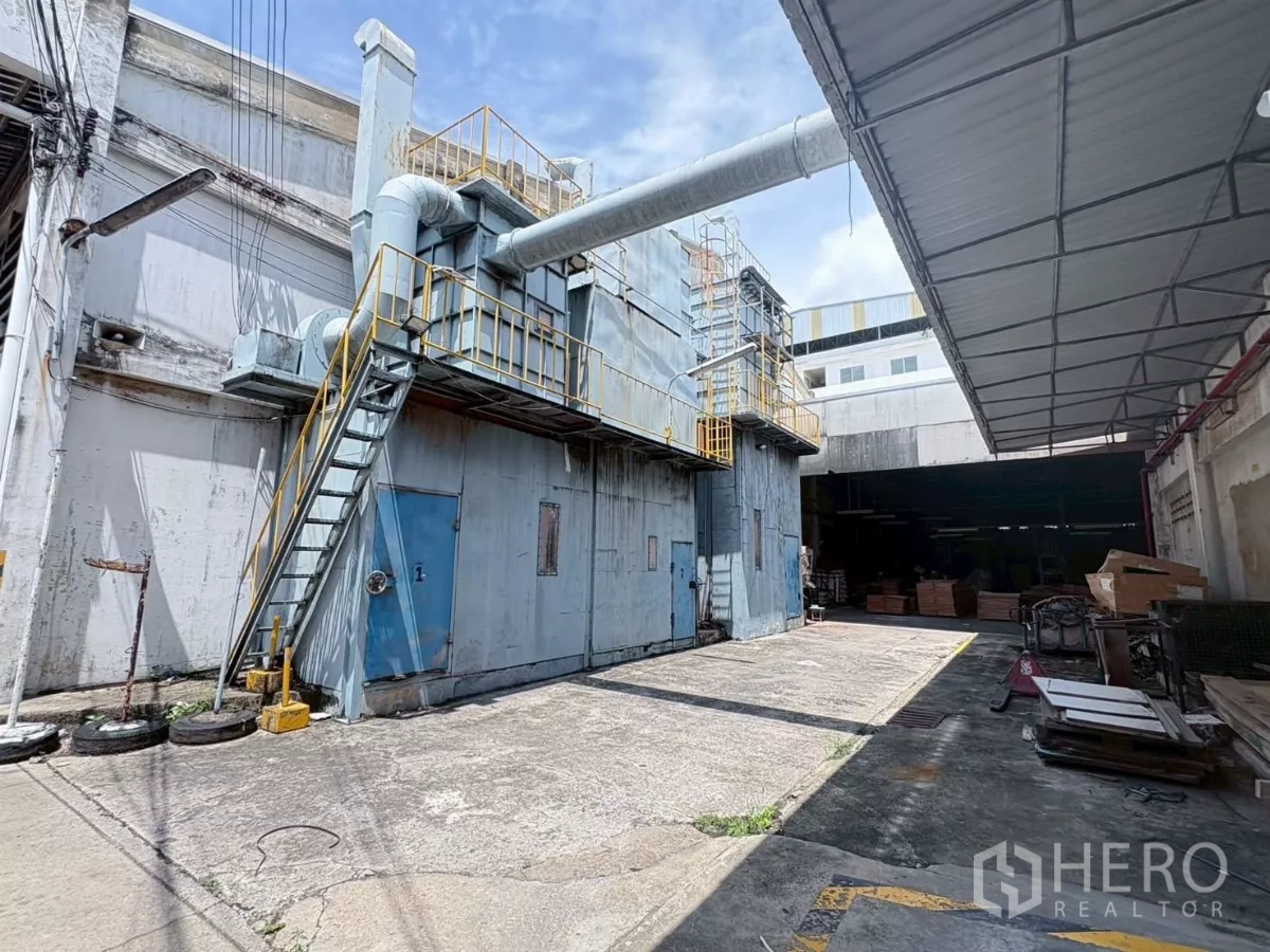 Factory for rent or sale in Bang Khun Thian, Bangkok - Industrial exhaust and ducting system mounted outside the building with metal stairs and service doors.
