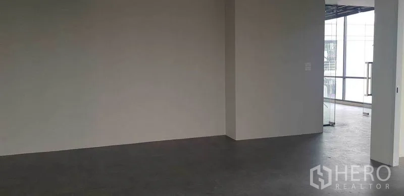 Office Space for rent in Suan Luang, Bangkok - Open-plan workspace with concrete-look flooring and neutral walls near the windowed facade.