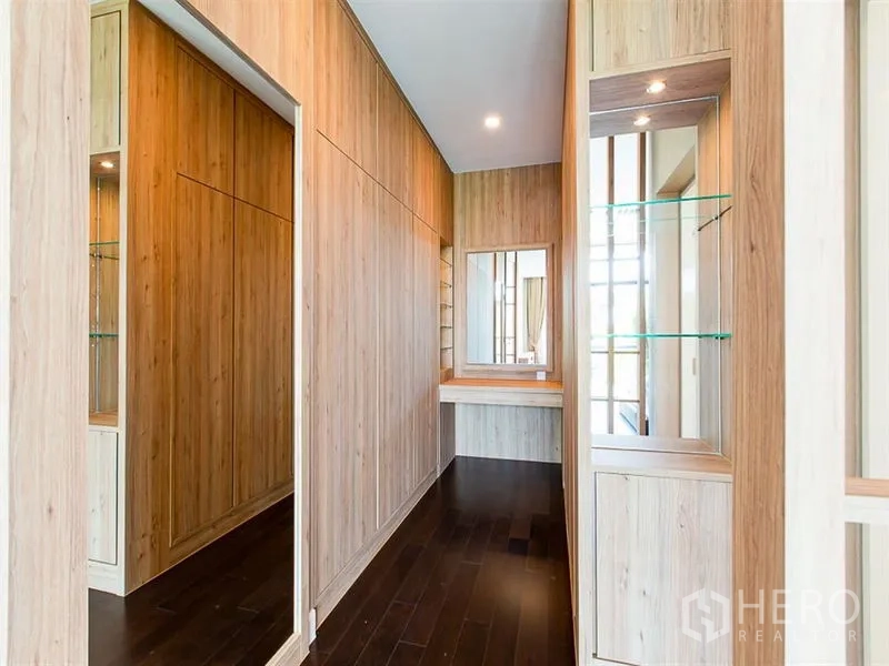 Detached House for rent or sale in Prawet, Bangkok - Walk-in closet corridor with floor-to-ceiling wood cabinets and a vanity.