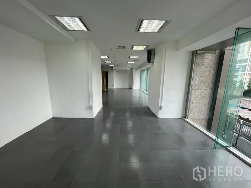 Office Space for rent - Bright corner of empty office showing white walls, columns, and a long run of windows.