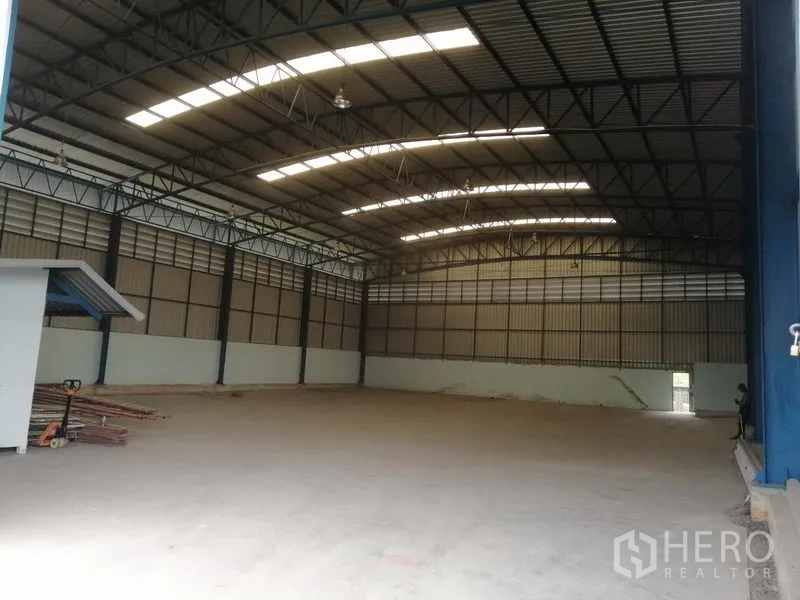 Warehouse for rent in Lat Krabang, Bangkok - Spacious warehouse interior in Lat Krabang with high steel truss roof, skylight panels, and smooth concrete floor.
