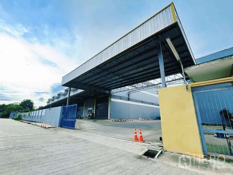 Factory for rent in Mueang Samut Sakhon, Samut Sakhon - Gated industrial entrance with wide ramp and large canopy for truck access.
