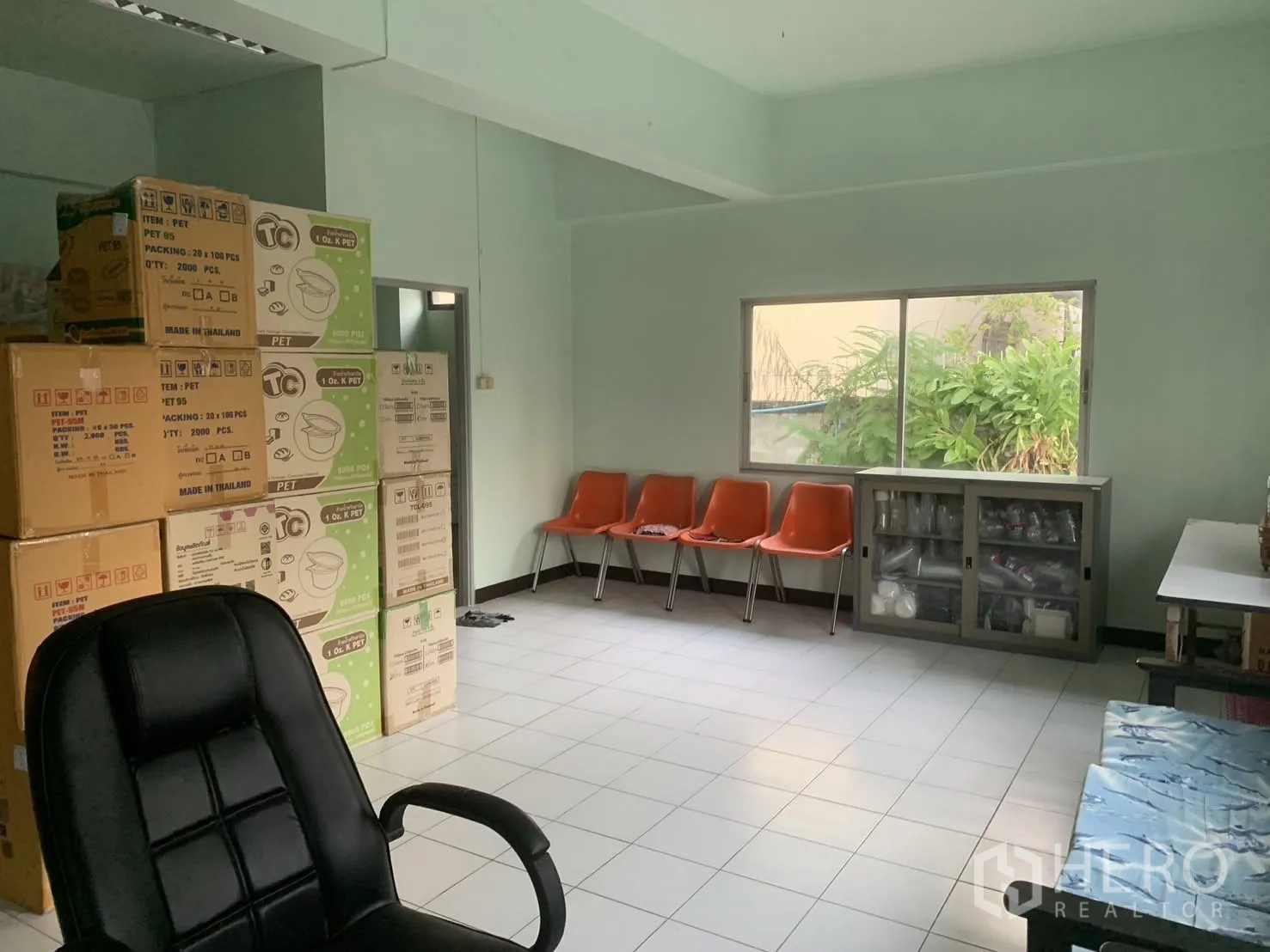 Warehouse for rent in Bang Phli, Samut Prakan - Office room with window, a row of chairs, and storage cabinet beside packing boxes.