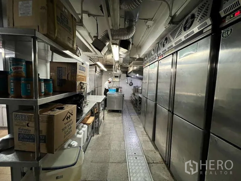 Shophouse for rent or sale in Khlong Toei, Bangkok - Narrow commercial kitchen aisle lined with industrial refrigerators and prep stations.