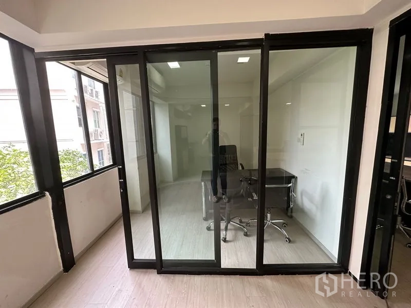 Office Space for rent in Khlong Toei, Bangkok - Private office with glass sliding doors, wood flooring, desk and chair, and leafy views.