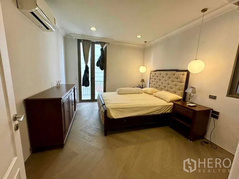 Townhouse for rent in Watthana, Bangkok - Cozy bedroom with tufted headboard, pendant lights and balcony access.