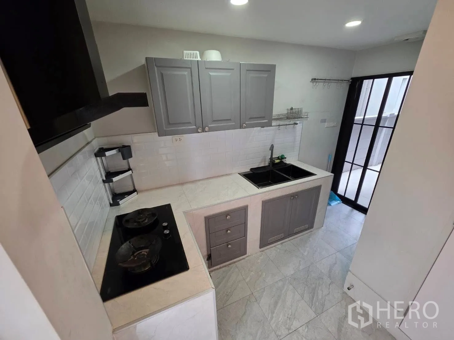 Detached House for rent or sale in Bang Phli, Samut Prakan - Compact gray built-in kitchen with double sink, gas hob and door to yard.