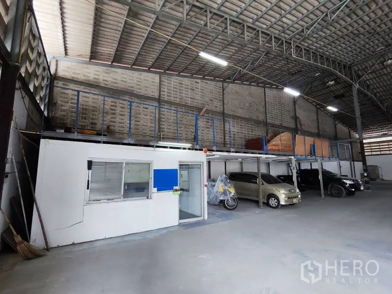 Warehouse for rent in Bang Phli, Samut Prakan - Internal office cabin with glass door beneath a mezzanine storage platform and covered parking.