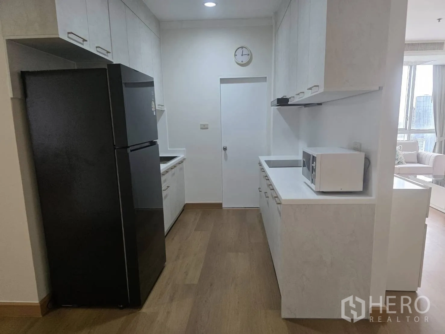Condominium for rent in Khlong Toei, Bangkok - Separate kitchen with white counters, ample storage and a black refrigerator.