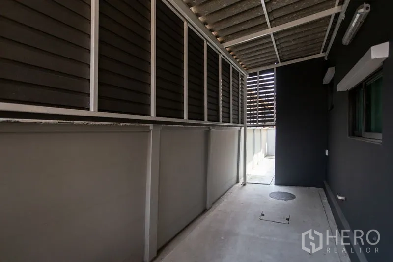 Townhouse for rent in Bang Phli, Samut Prakan - Covered utility area at the side of the house with a roofed walkway and ventilation panels.