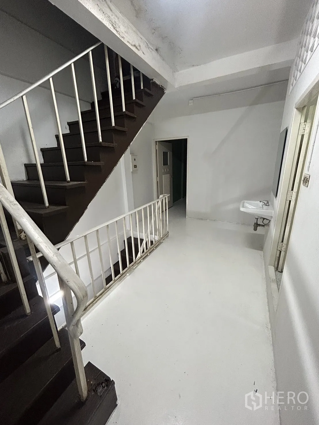 Shophouse for rent in Khlong Toei, Bangkok - Internal staircase with white railings and a washbasin on the landing.