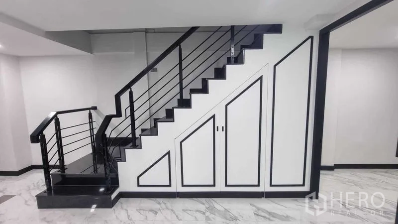 Townhouse for rent in Khlong Toei, Bangkok - Modern staircase with black rails and built-in storage beneath the stairs.