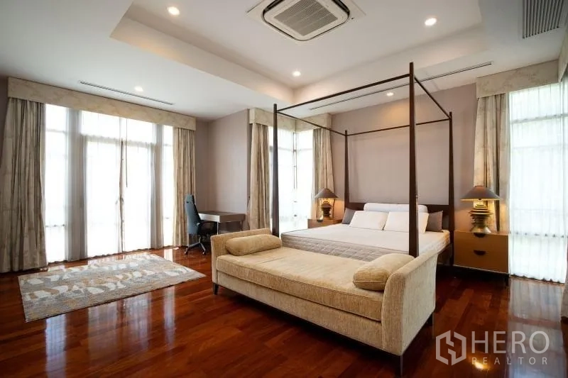 Detached House for rent in Watthana, Bangkok - Spacious master bedroom with four-poster bed, sofa bench and polished wood floors.