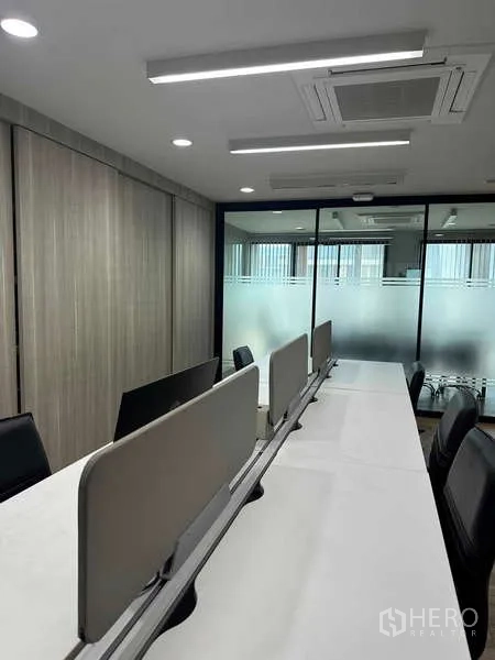 Home Office for rent in Bueng Kum, Bangkok - Sunlit reception seating area with sofa, ottoman, and street view through floor-to-ceiling windows.