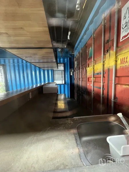 Retail Space for rent - Back-of-house prep area featuring a sink, long countertop and container wall panels.