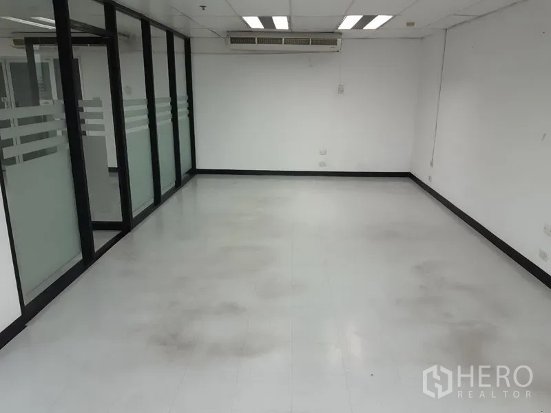 Office Space for rent in Watthana, Bangkok - Empty office area with glass partitions and ceiling air-conditioning units.