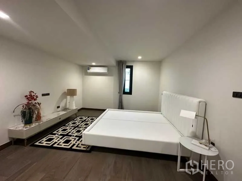 独立式住宅 出租在Suan Luang, Bangkok - 极简卧室，白色床架、边几与木地板。