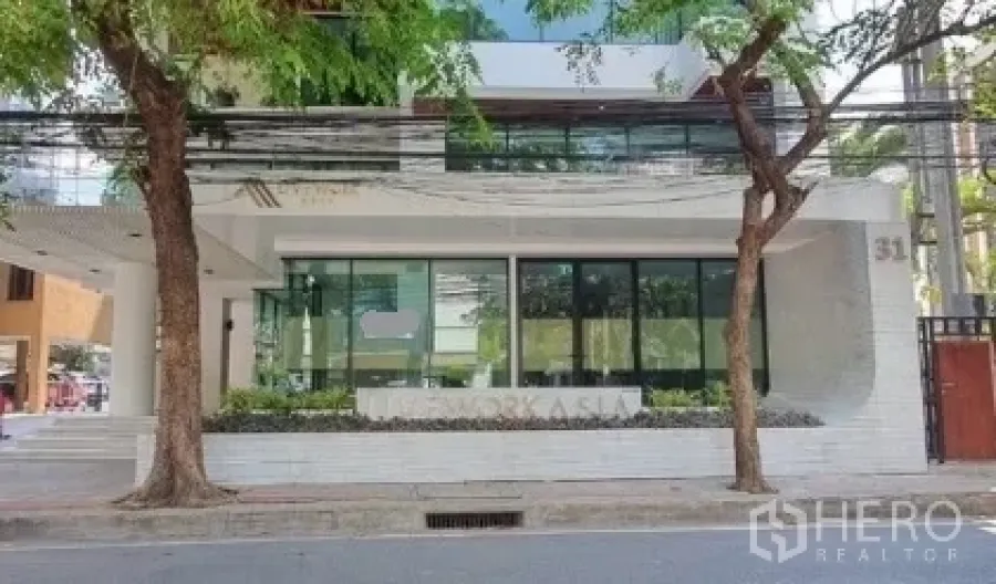 零售空间 出租在Khlong Toei, Bangkok - 建筑正面全景：一层玻璃店铺、行道树与街景。