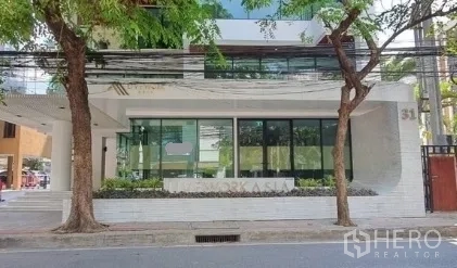 Retail Space for rent in Khlong Toei, Bangkok - Full frontage of a modern building showing a ground-floor glass retail space, mature street trees, and a city street view.