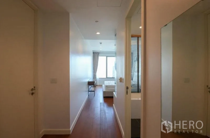 Condominium for rent in Pathum Wan, Bangkok - Hallway with wood floors leading to a bedroom and bathroom entrance.