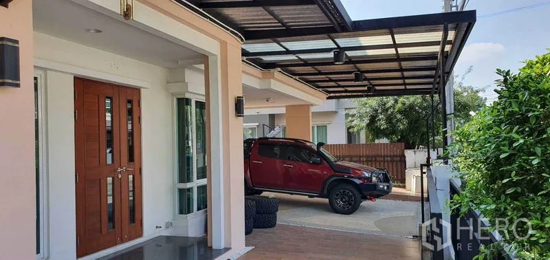 Detached House for sale in Khan Na Yao, Bangkok - Front exterior with double wooden entrance door and a wide covered carport.