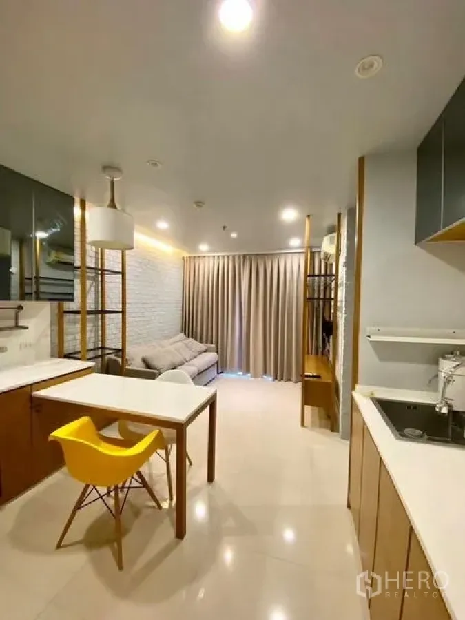 Condominium for rent in Chatuchak, Bangkok - Living and kitchenette overview with dining table, pendant light and ample storage.
