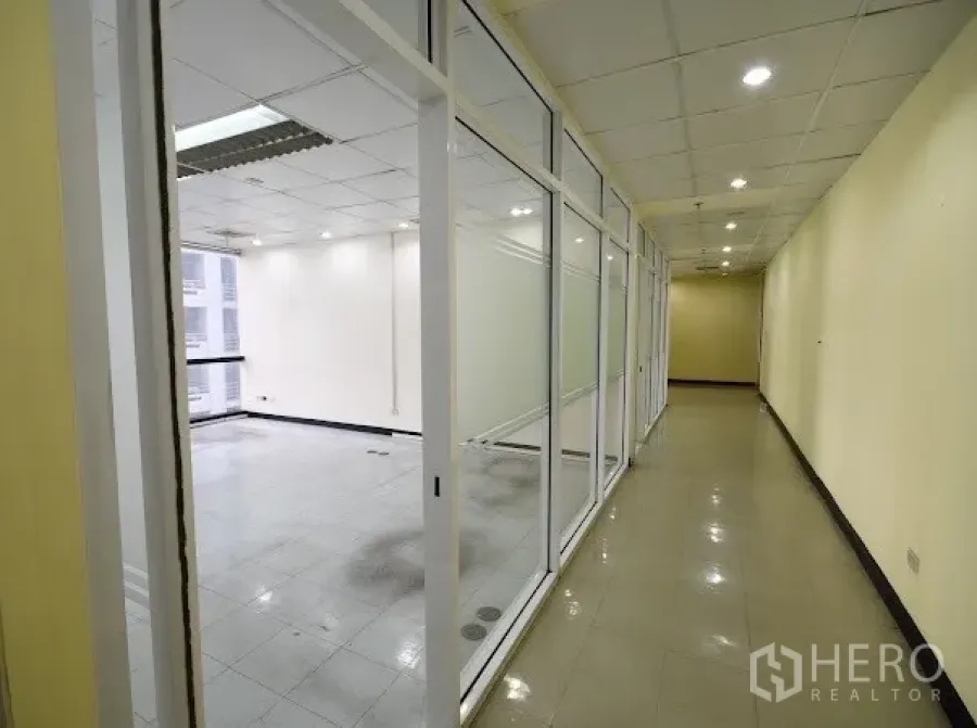 Office Space for rent in Watthana, Bangkok - Bright corridor with glass-partitioned offices and recessed lights in a Sukhumvit business building.