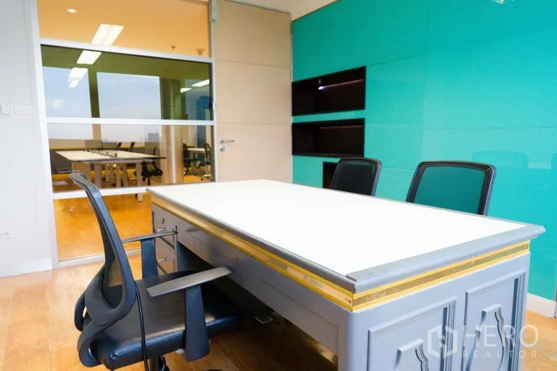 Office Space for rent - Small meeting room with glass door, teal accent wall and office chairs.