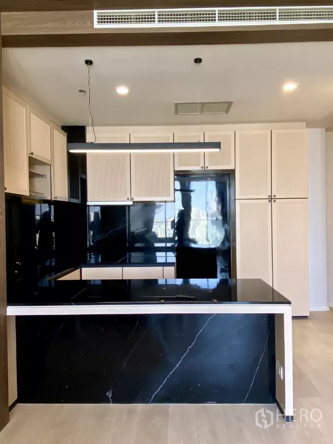 Condominium for sale in Pathum Wan, Bangkok - Front view of kitchen showing black marble island, tall storage, and integrated appliances.