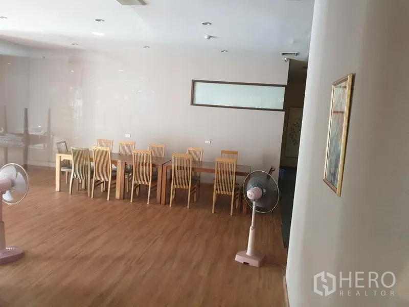 Retail Space for rent in Khlong Toei, Bangkok - Open-plan dining area with a long wooden table, matching chairs and fans on wood flooring.