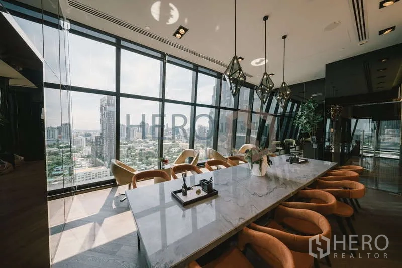 Condominium for rent - Sky lounge dining area featuring a long marble table, pendant lights and panoramic city views.