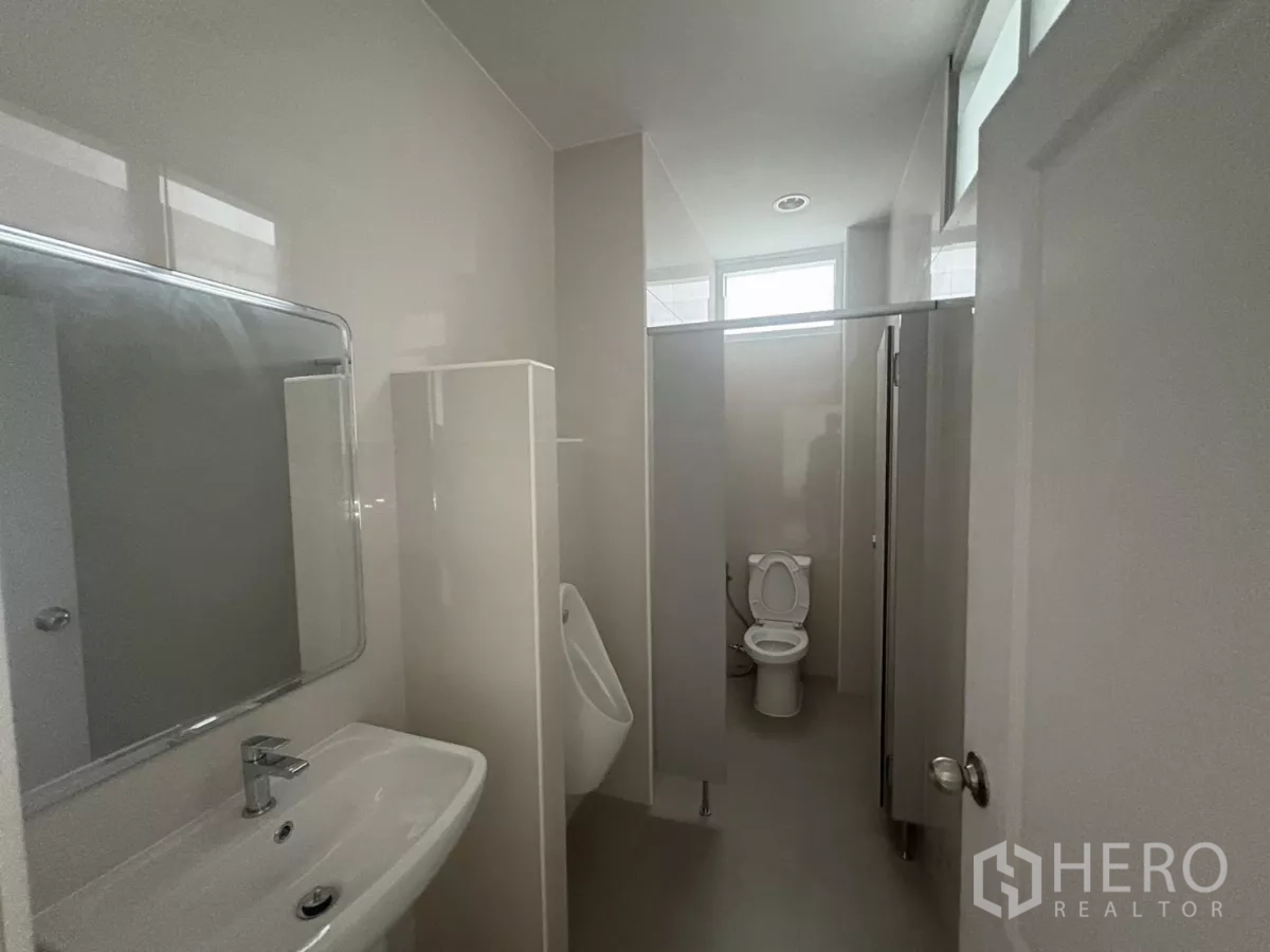 Factory for rent in Bang Phli, Samut Prakan - Restroom with a urinal, toilet stalls, and a washbasin under bright lighting.