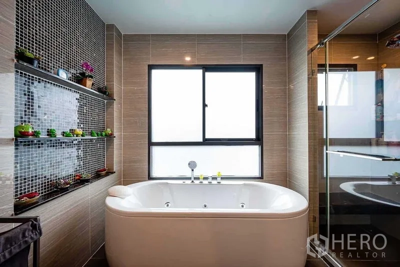 Detached House for sale in Prawet, Bangkok - Bathroom with jetted bathtub, tiled walls and glass shower.