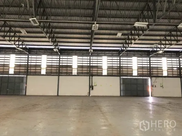 Warehouse for rent in Khlong Luang, Pathum Thani - Interior wall with multiple louvered panels and sliding doors allowing natural light, plus visible electrical units.