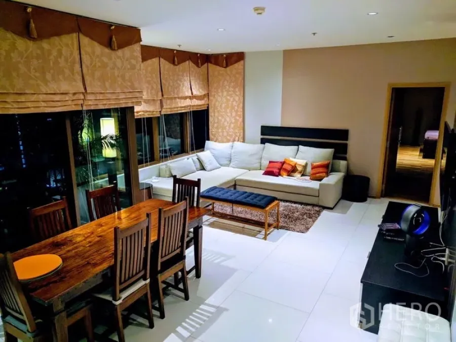 Condominium for rent - Another angle of the living area with sectional sofa, TV console, and city-view windows.