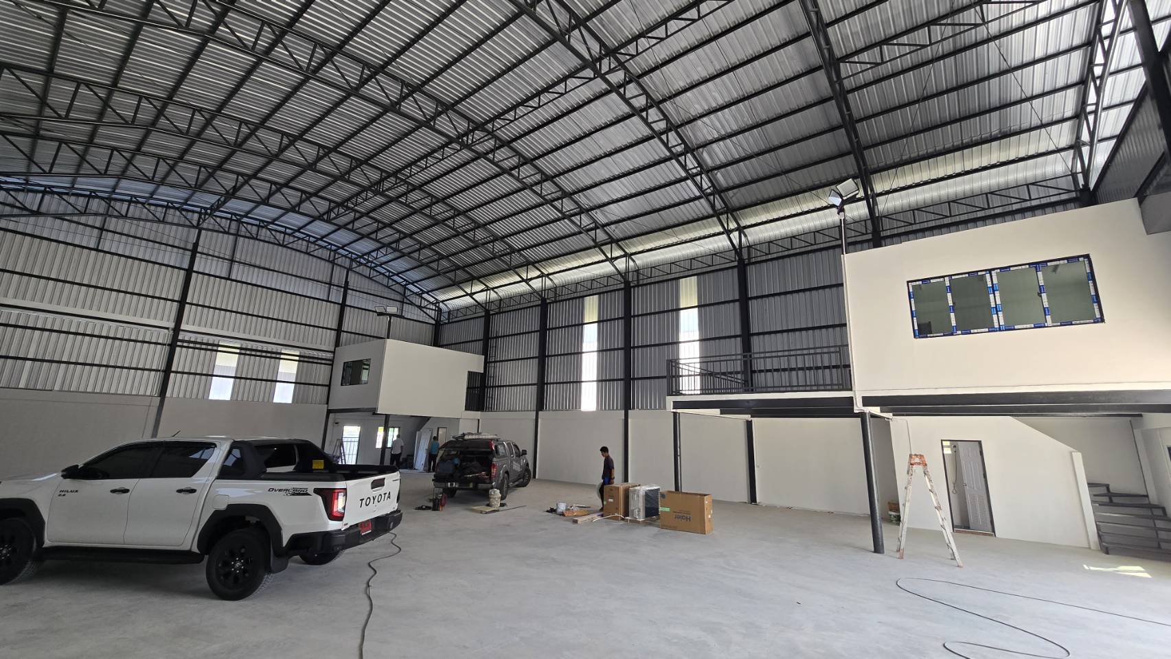 Warehouse for rent in Bang Phli, Samut Prakan - Spacious warehouse interior featuring a high arched steel roof, polished concrete floor, mezzanine office pods, and a large loading bay.