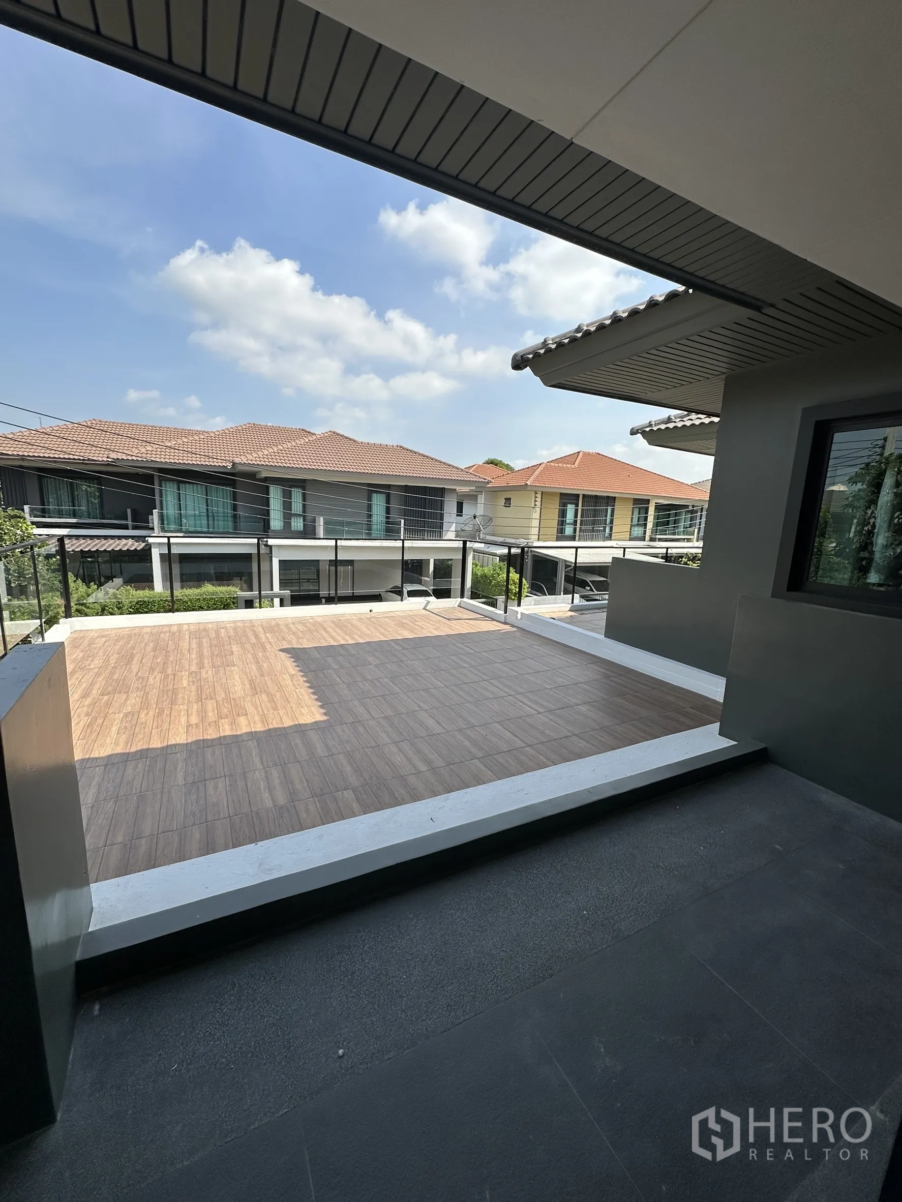 Detached House for sale in Lam Luk Ka, Pathum Thani - Second-floor terrace with tiled deck and neighborhood view under a blue sky.
