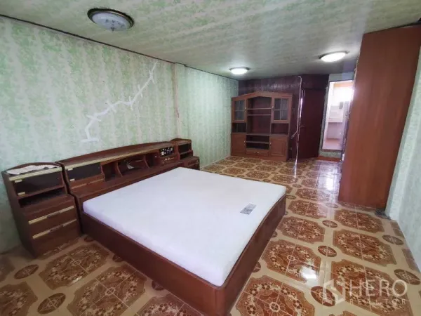Shophouse for rent in Suan Luang, Bangkok - Spacious bedroom with vintage tiled floor, green wallpaper and built-in wooden bed.