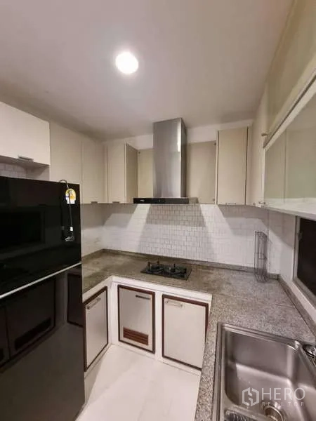 Detached House for rent in Bang Kruai, Nonthaburi - Compact L-shaped kitchen with gas hob, hood, granite countertops and storage cabinets.