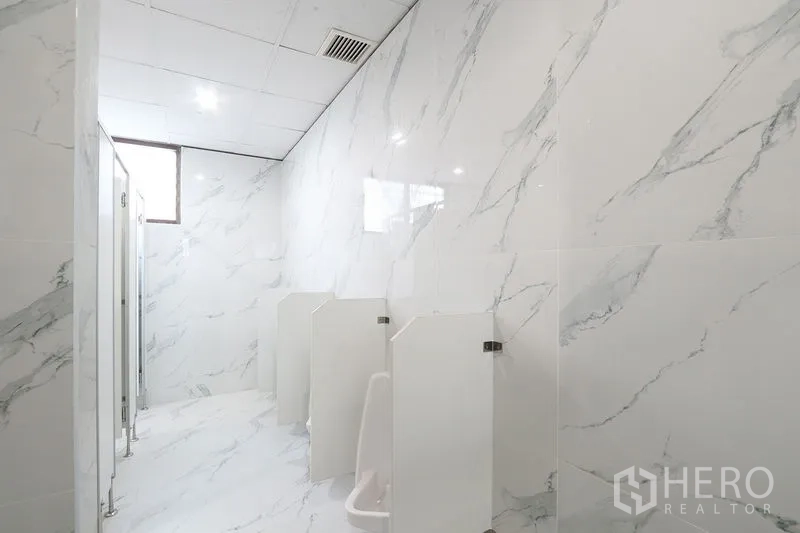 Office Space for rent in Bang Na, Bangkok - Clean bathroom area with marble walls, urinals and private stalls inside the office building.