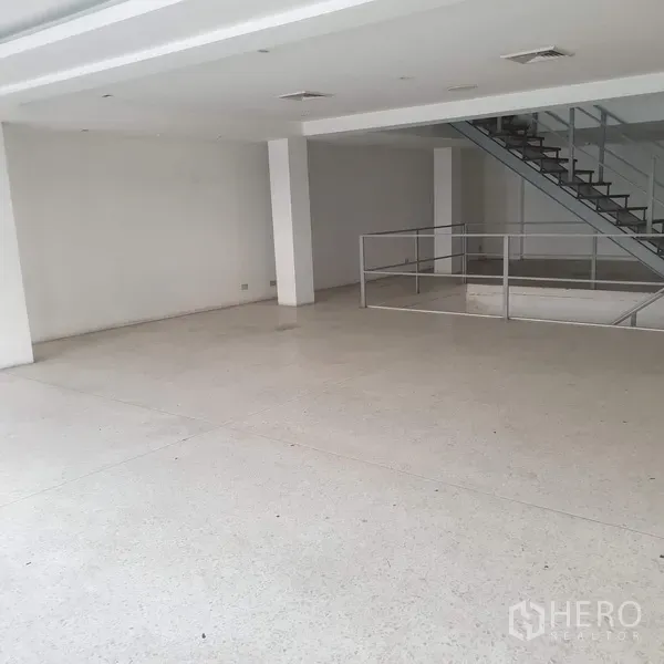 Home Office for rent in Khlong Toei, Bangkok - Spacious white workspace with mezzanine void and stair access.