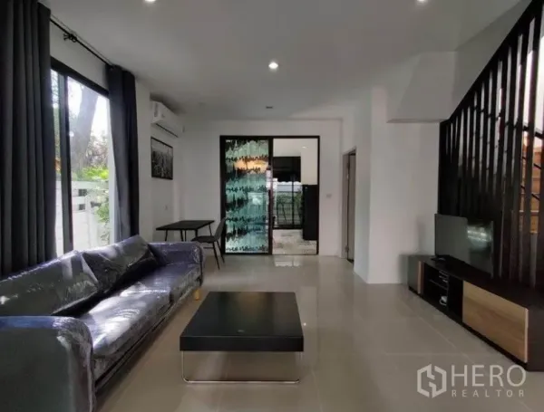 Townhouse for rent in Suan Luang, Bangkok - Open living room with sliding glass door and an accent glass partition.