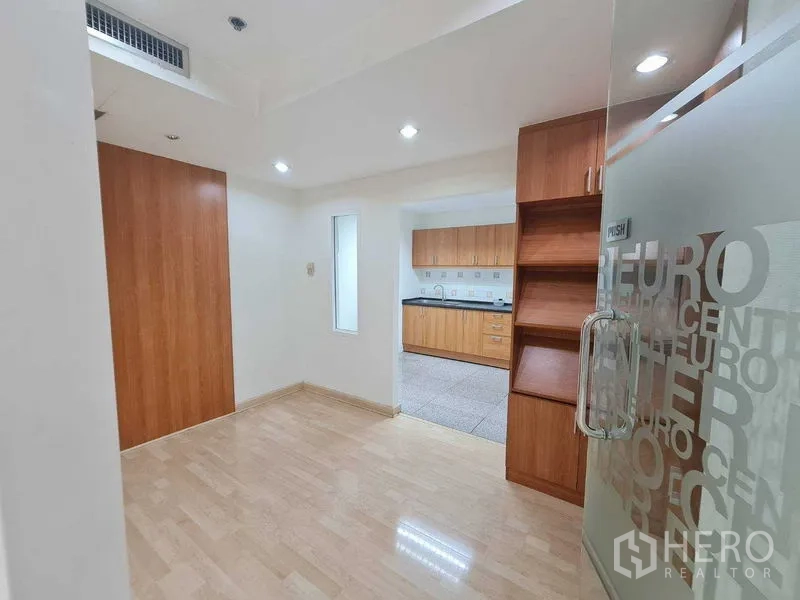 Office Space for rent in Ratchathewi, Bangkok - Reception nook with glass door, light wood flooring, built-in shelving and a pantry beyond.