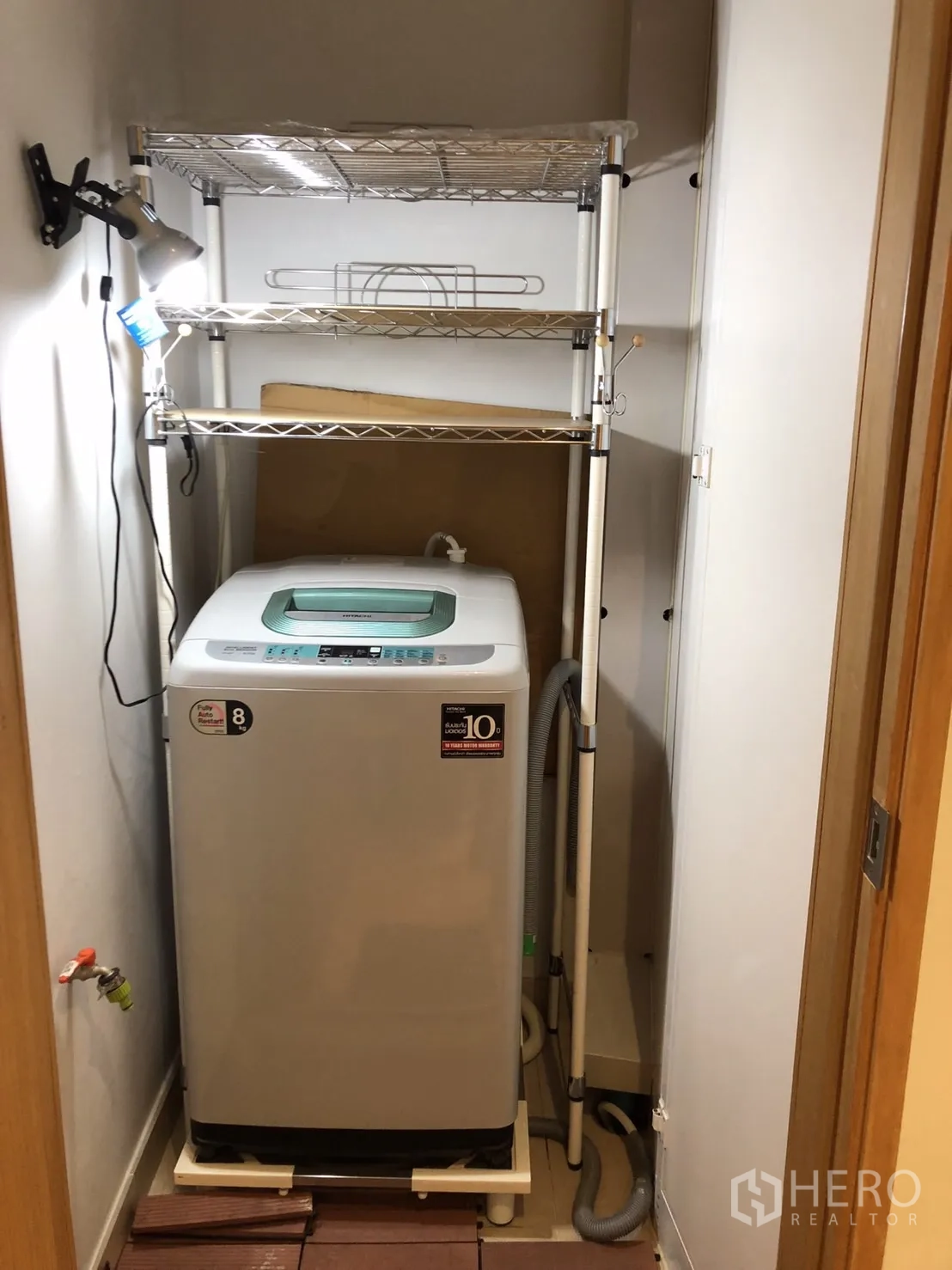 Condominium for rent or sale in Khlong Toei, Bangkok - Compact laundry closet with top-loading washing machine and metal shelving.