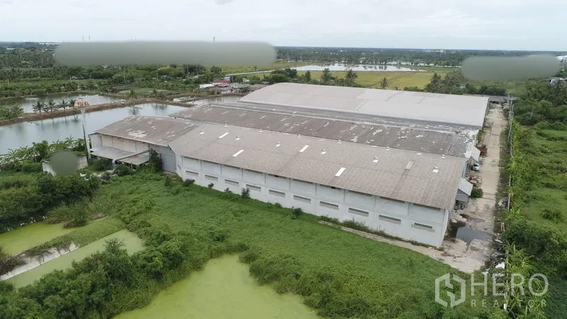 Factory for rent or sale in Krathum Baen, Samut Sakhon - Aerial view of an expansive factory complex surrounded by canals and green fields in Krathum Baen.