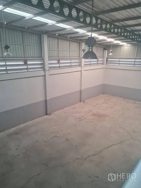 Factory for rent or sale in Lam Luk Ka, Pathum Thani - High-ceiling warehouse bay with concrete floor and hanging industrial lights.