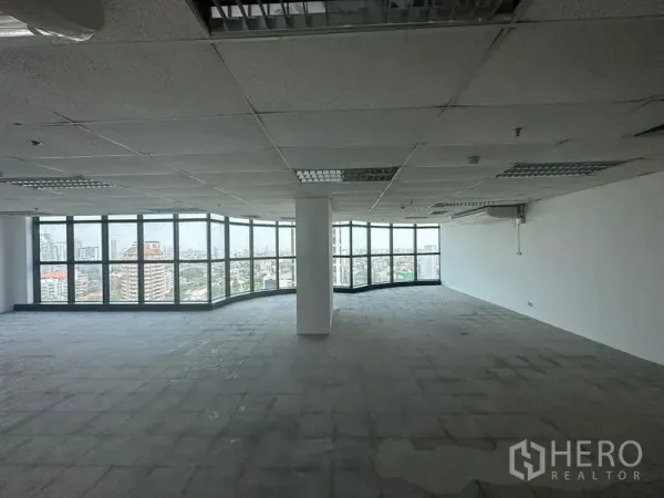 Office Space for rent - Large open‑plan office floor with central column and panoramic glass windows overlooking the city.