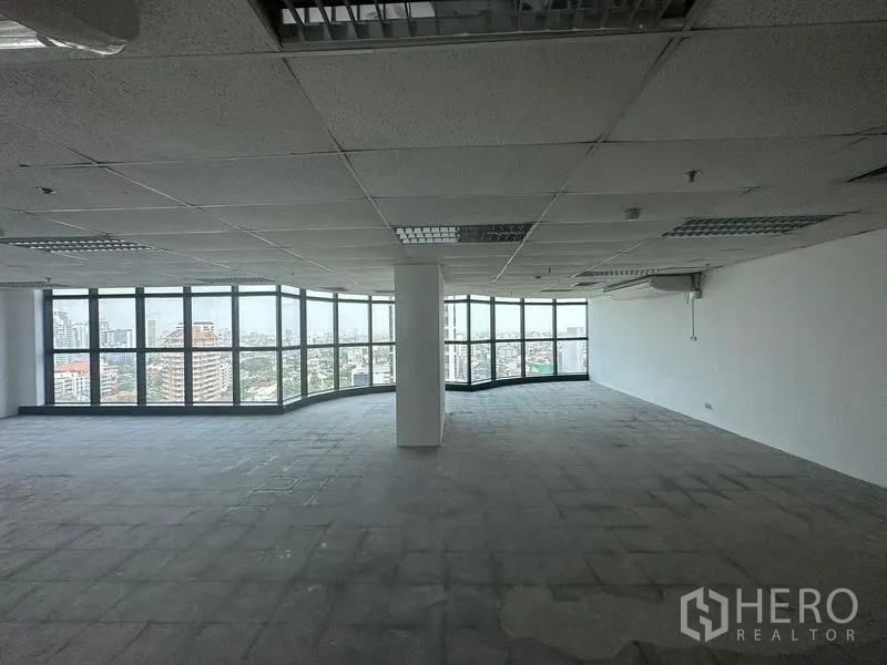 Office Space for rent - Large open‑plan office floor with central column and panoramic glass windows overlooking the city.