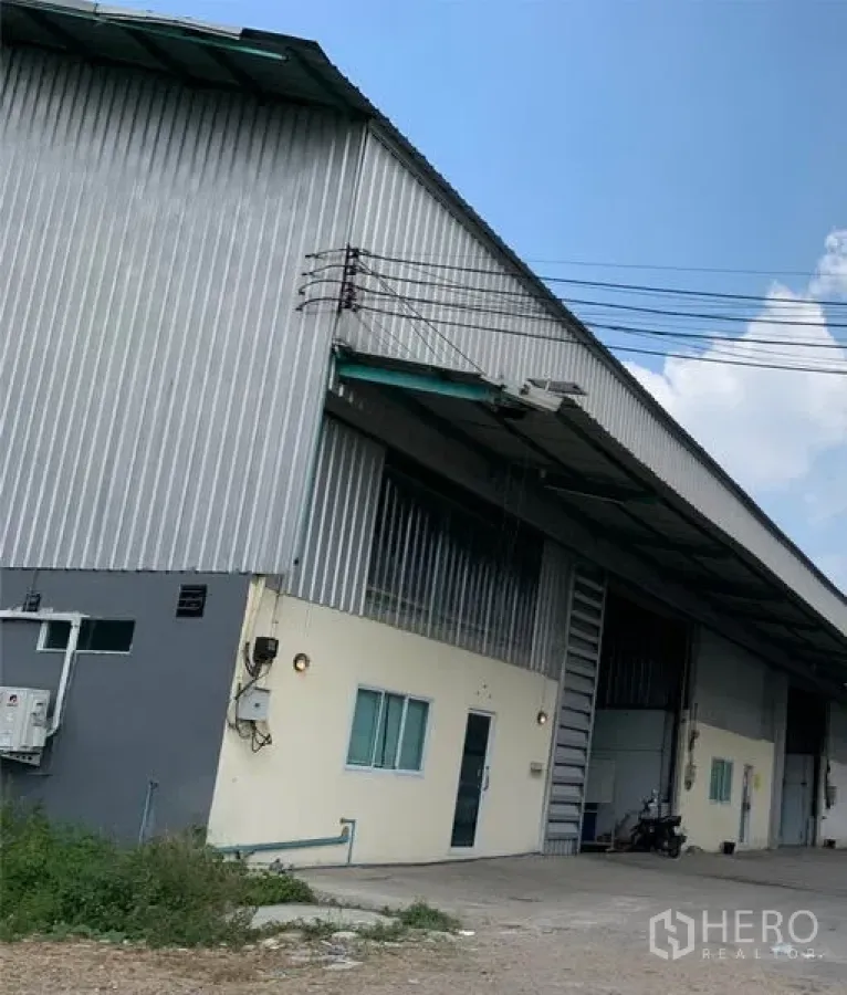คลังสินค้า ให้เช่าในKhlong Luang, Pathum Thani - ด้านนอกโกดังผนังเมทัลชีท มีชายคาสำหรับขนถ่ายสินค้า หน้าต่างออฟฟิศ และทางเข้า ในย่านคลองหลวง