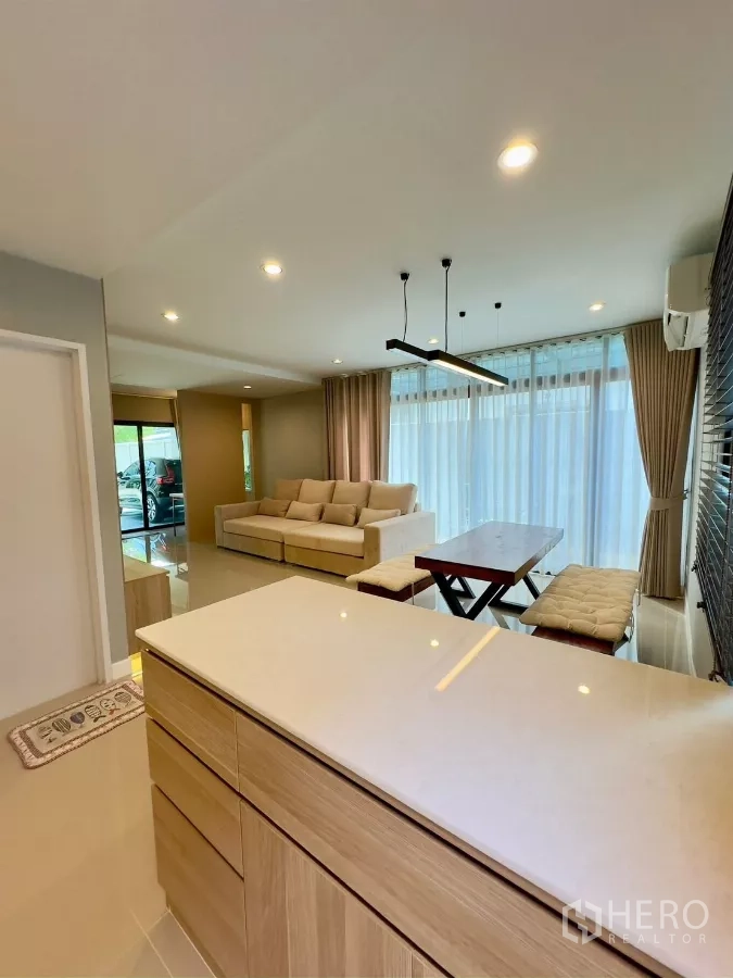 Detached House for rent in Samut Prakan - View from the kitchen island to bright living and dining space with sheer curtains.